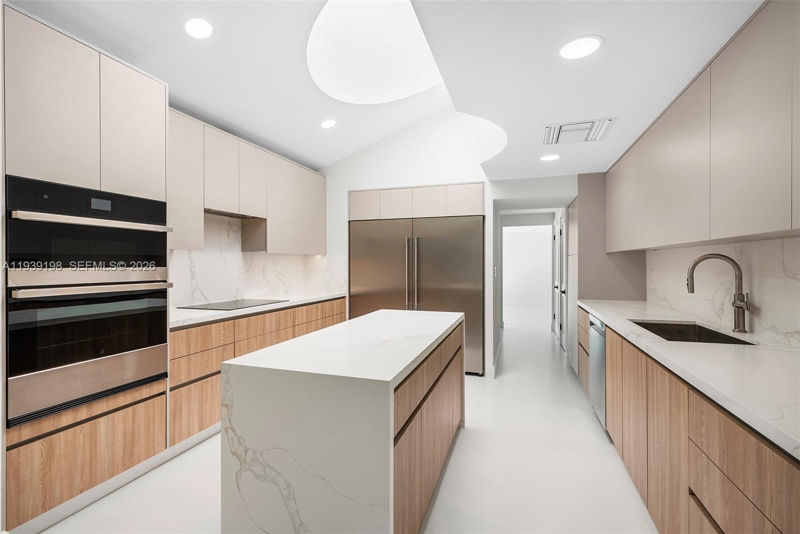 A modern kitchen features light wood cabinetry, white marble countertops, and stainless steel appliances — 7540 Los Pinos Blvd, Coral Gables FL 33143, CORAL GABLES, FL