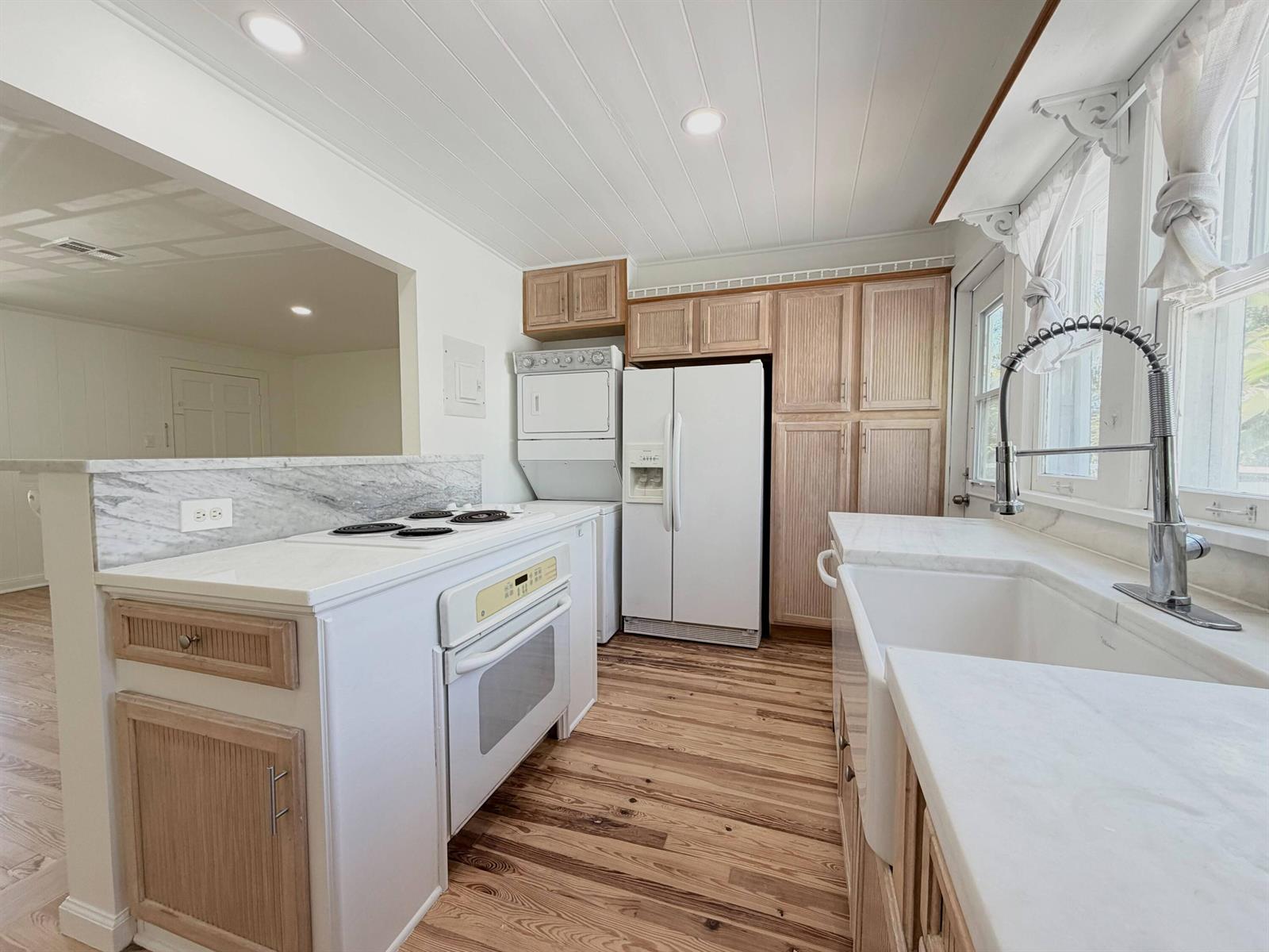 A kitchen features white countertops, wood cabinets, a farmhouse sink, and a stacked laundry unit — 1713 Florida Avenue # A2, West Palm Beach FL 33401, WEST PALM BEACH, FL