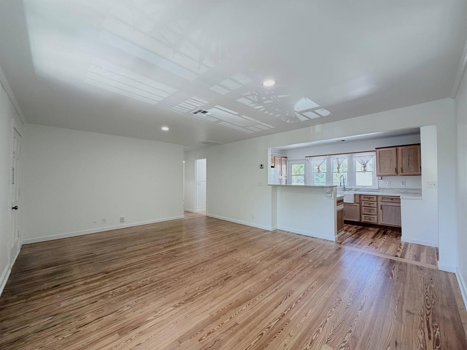 An open-concept living room with hardwood floors leads into a kitchen with wood cabinets — 1713 Florida Avenue # A2, West Palm Beach FL 33401, WEST PALM BEACH, FL