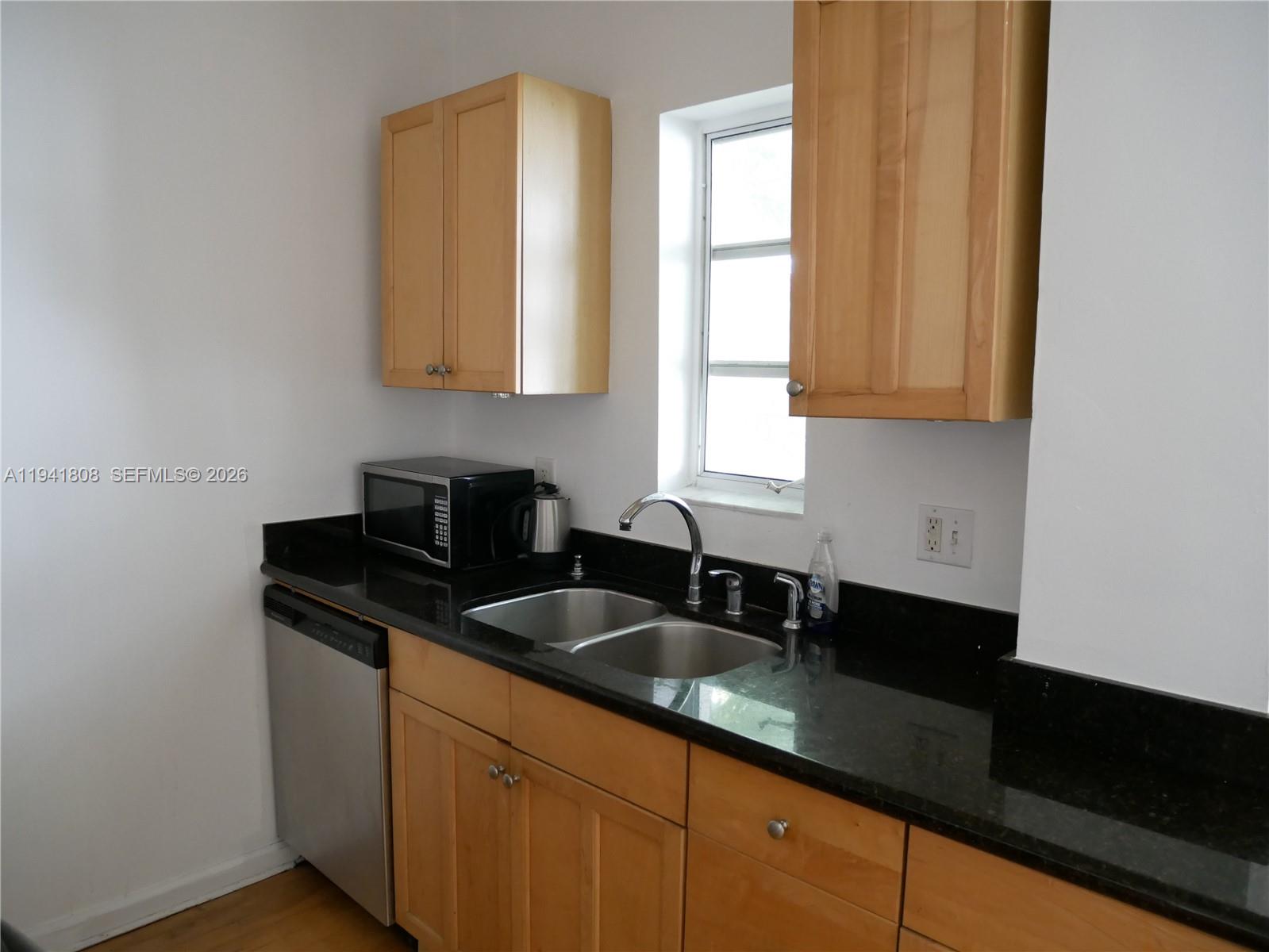 A kitchen features light wood cabinets, black countertops, a double sink, and stainless steel appliances — 631 Euclid Ave # 7, Miami Beach FL 33139, MIAMI BEACH, FL