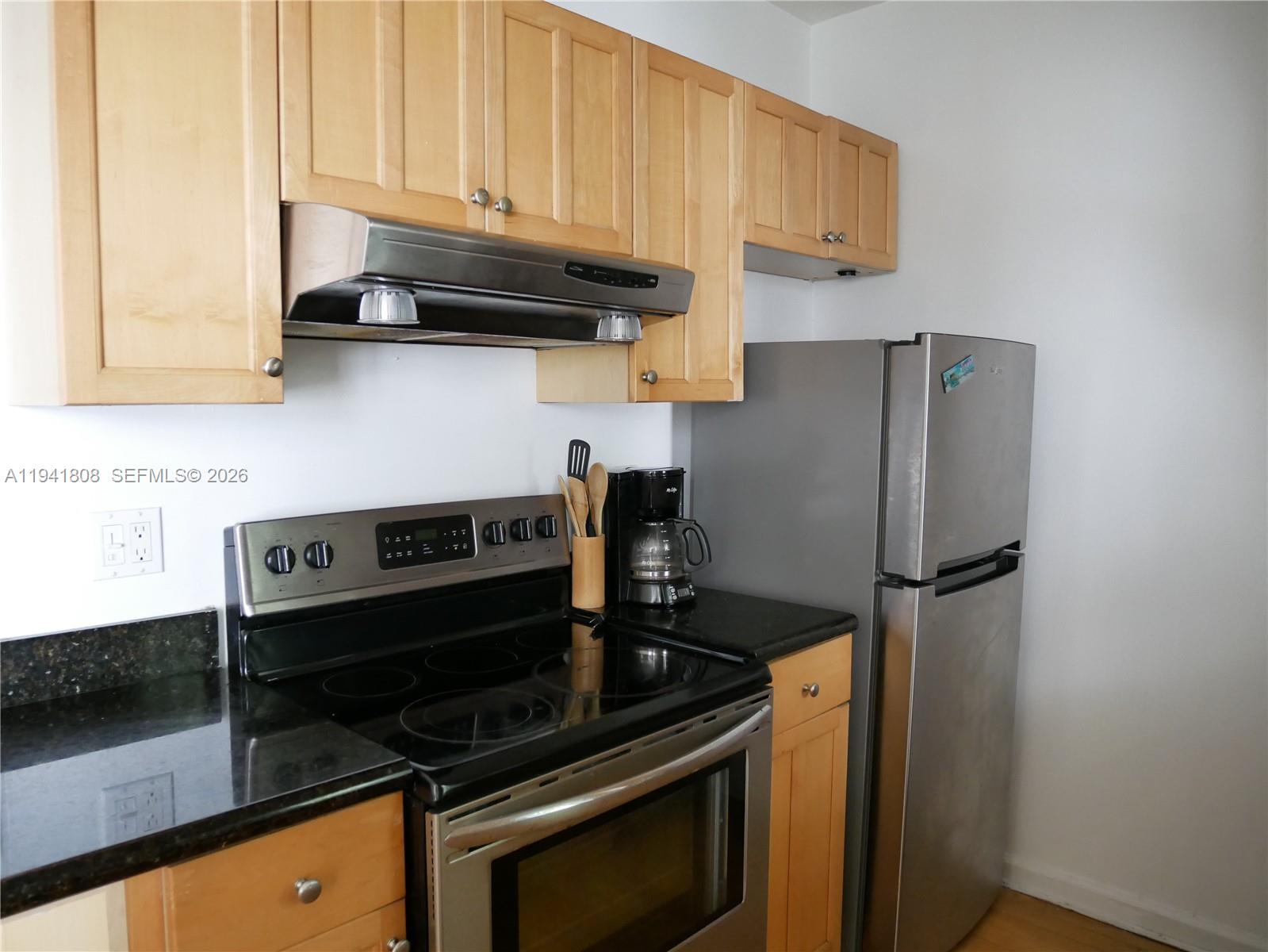 A kitchen features light wood cabinets, stainless steel appliances, and black granite countertops — 631 Euclid Ave # 7, Miami Beach FL 33139, MIAMI BEACH, FL