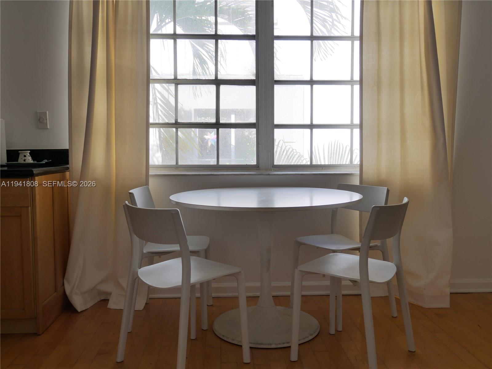 A dining area features a white pedestal table and four chairs in front of a window — 631 Euclid Ave # 7, Miami Beach FL 33139, MIAMI BEACH, FL