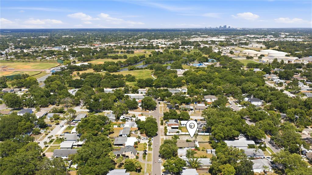 An aerial view shows a suburban neighborhood with a marked property and distant city skyline — 8056 28TH AVENUE N, ST PETERSBURG, FL