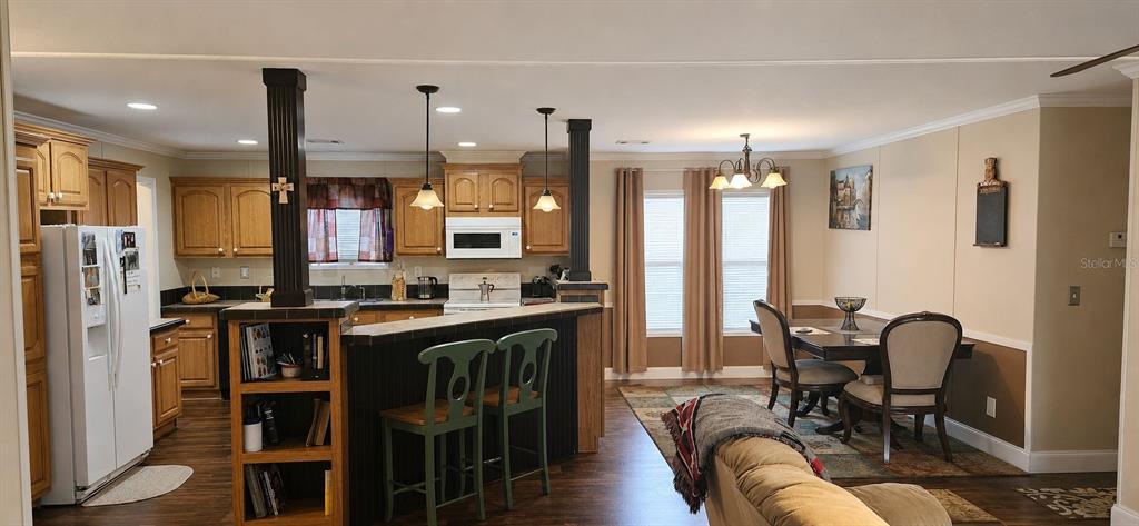 An open-concept kitchen and dining area features wood cabinets, a breakfast bar, and pendant lighting — 11005 SE 165TH TERRACE ROAD, OCKLAWAHA, FL