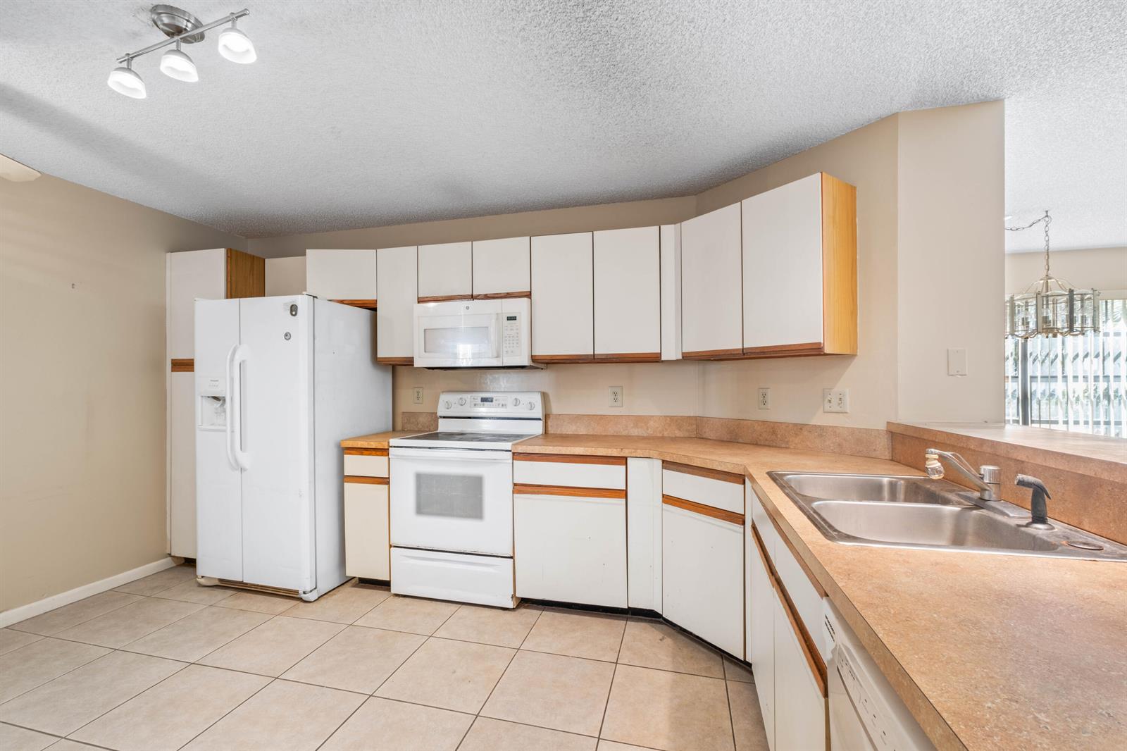 A kitchen with white cabinets, white appliances, tan countertops, and light-colored tile flooring — 3237 Perimeter Drive # 2512, FL 33467, FL