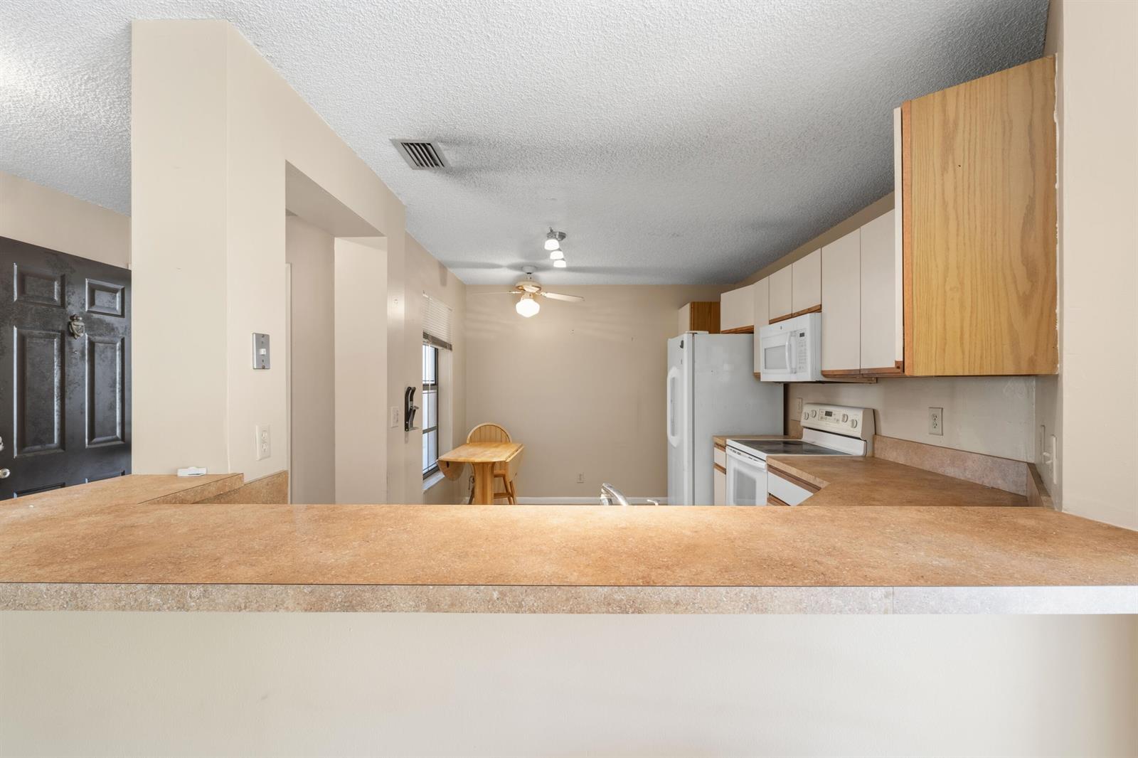 A kitchen with light-colored cabinets, laminate countertops, and an adjacent dining area — 3237 Perimeter Drive # 2512, FL 33467, FL