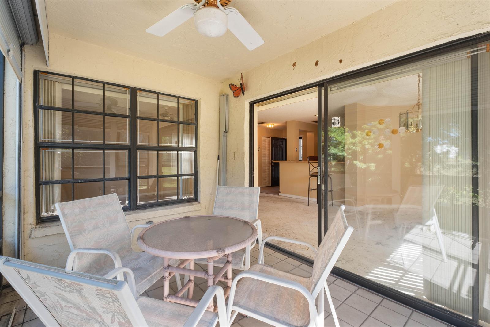 A covered patio features a glass-topped table, four chairs, a ceiling fan, and sliding doors — 3237 Perimeter Drive # 2512, FL 33467, FL