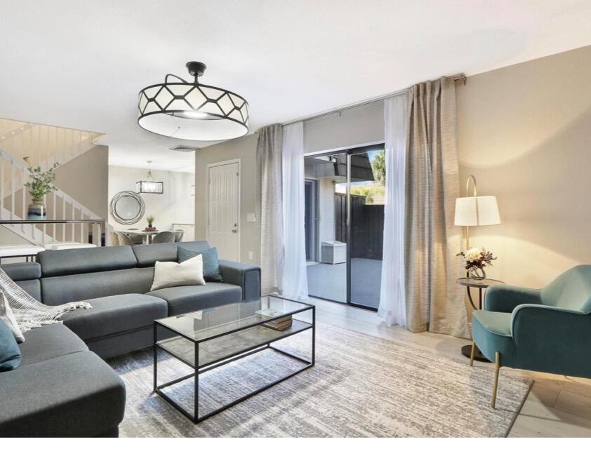 A living room features a grey sectional sofa, glass coffee table, and a teal armchair — 2117 21st Court, Jupiter FL 33477, JUPITER, FL