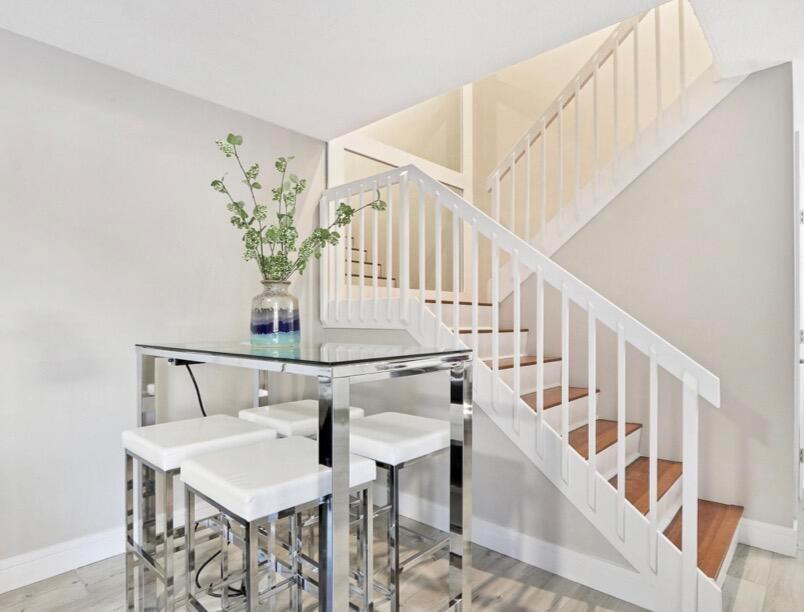 A glass-topped table with four stools sits beside a wooden staircase with white railings — 2117 21st Court, Jupiter FL 33477, JUPITER, FL