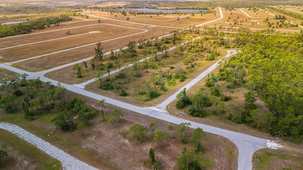 An aerial view shows a network of paved roads winding through a vacant, wooded residential lot — 12482 PORKFISH COURT, PLACIDA, FL