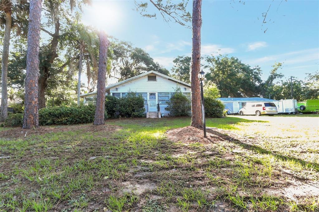A single-story house with a screened porch sits on a grassy lot with tall trees — 917 OXFORD STREET, LONGWOOD, FL