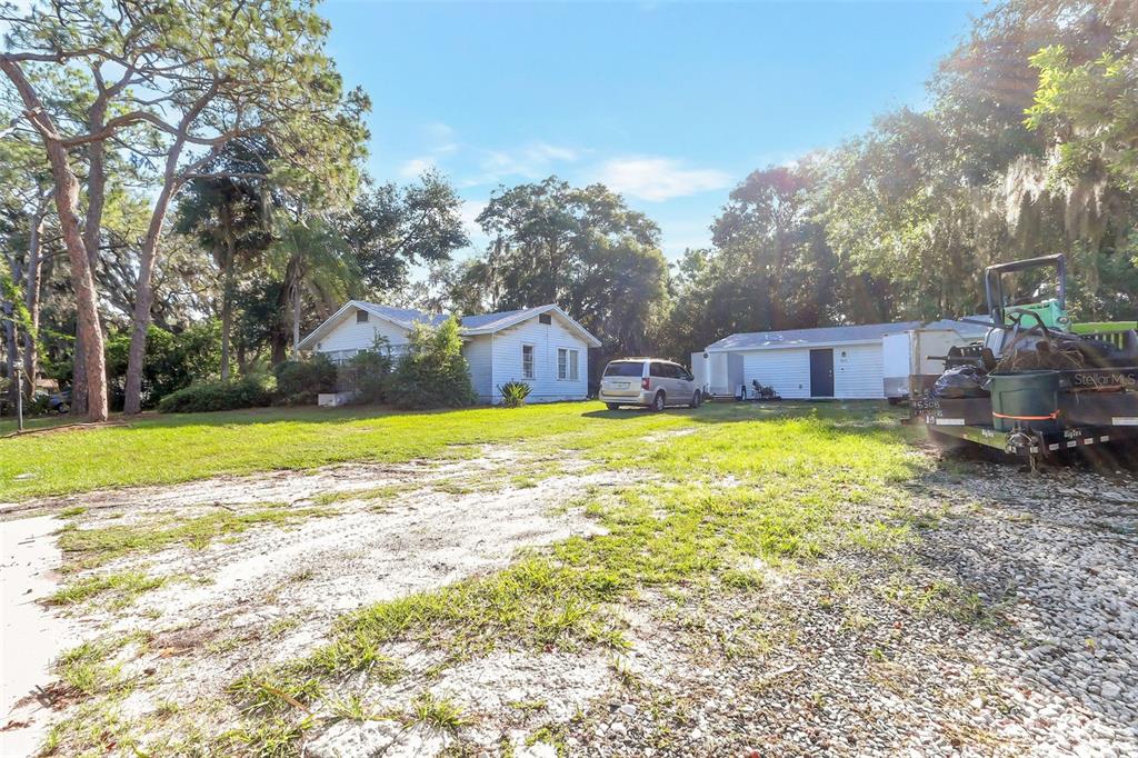 A gravel driveway leads to two white houses with a trailer parked on the right — 917 OXFORD STREET, LONGWOOD, FL