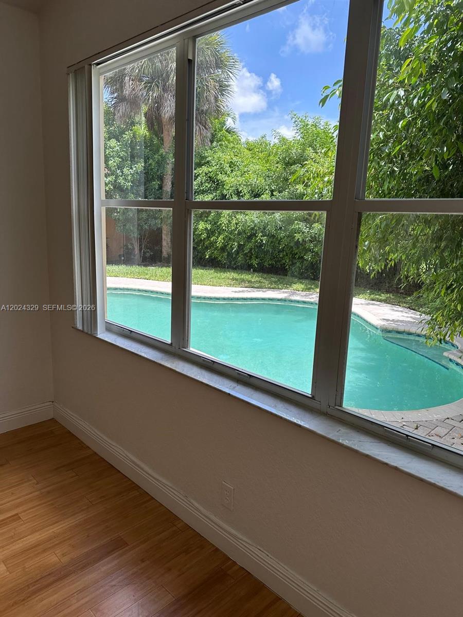 A view of a backyard swimming pool through a large window in a room — 11090 Baybreeze Way # 11090, Boca Raton FL 33428, BOCA RATON, FL