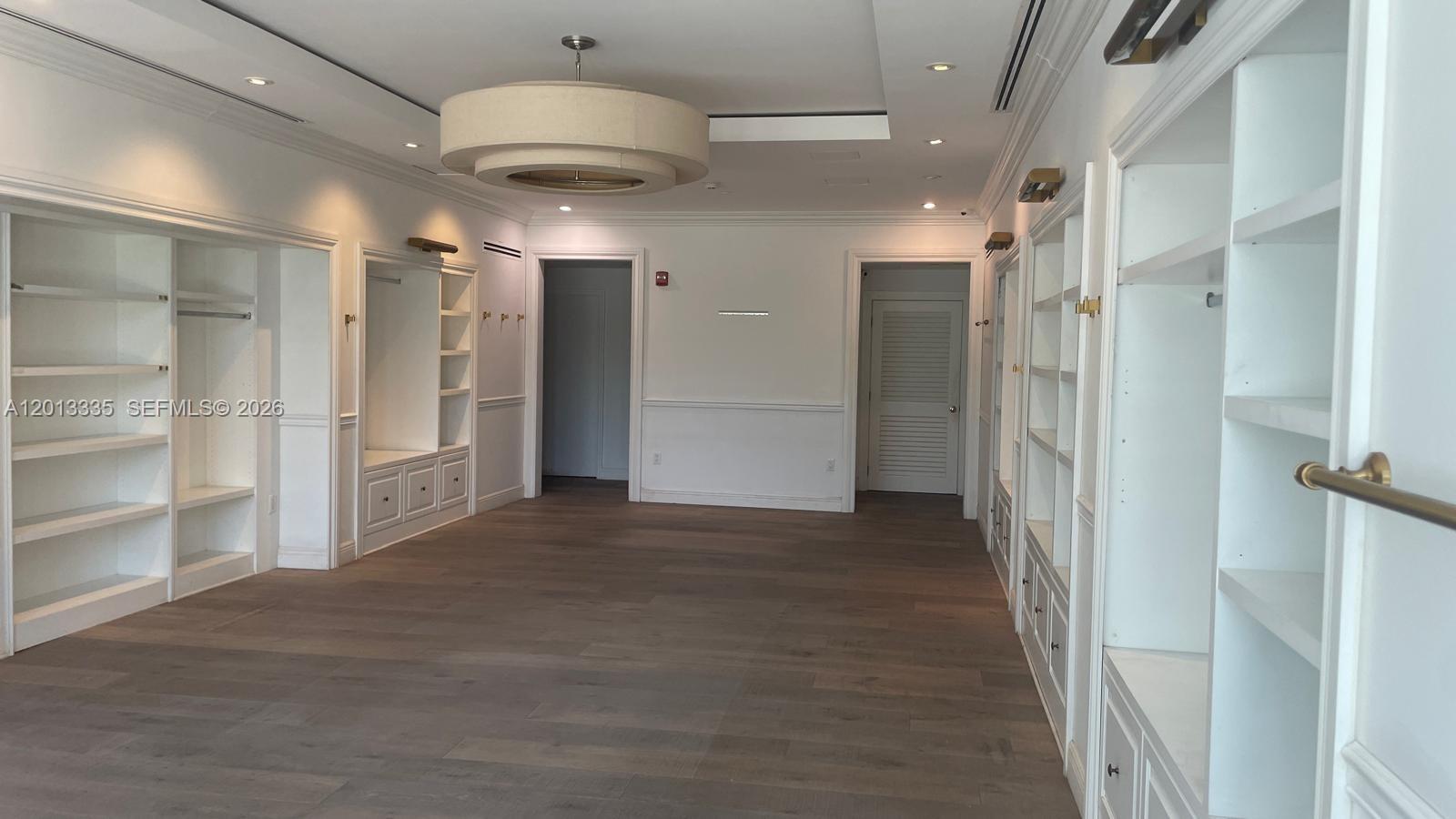A spacious walk-in closet features white built-in shelving, wooden flooring, and a large pendant light — 1201 20th St # 7, Miami Beach FL 33139, MIAMI BEACH, FL