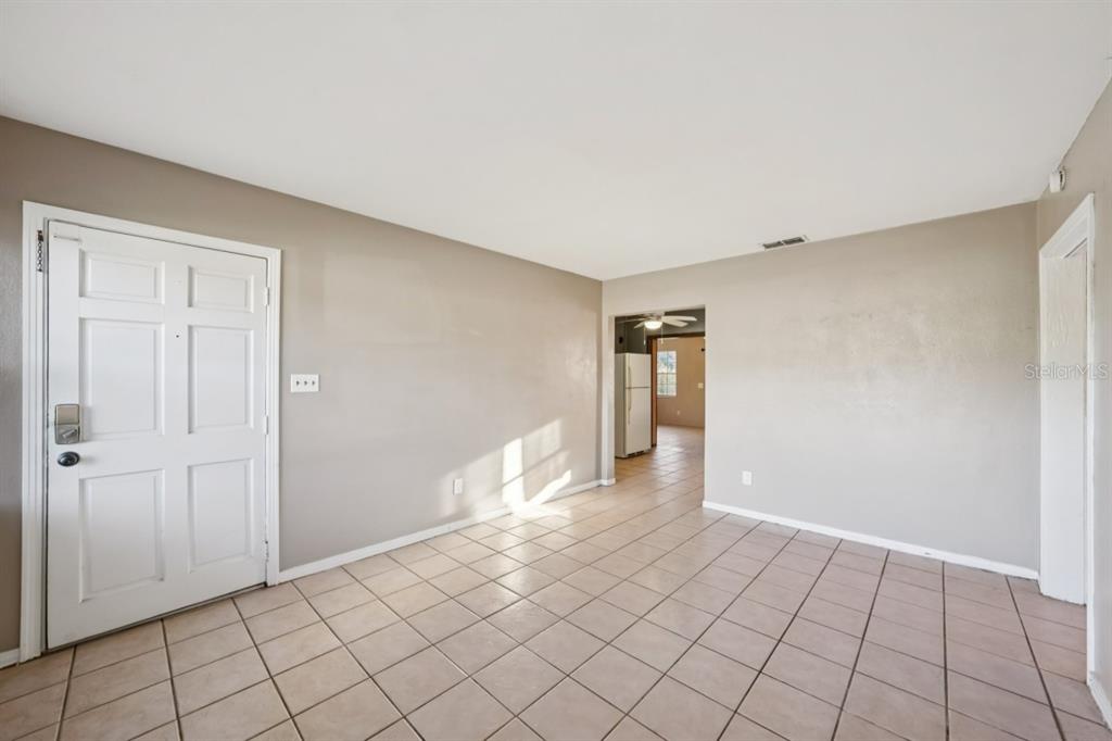 An empty room with beige walls, white trim, and light-colored square floor tiles — 603 OAK RIDGE DRIVE, BRANDON, FL