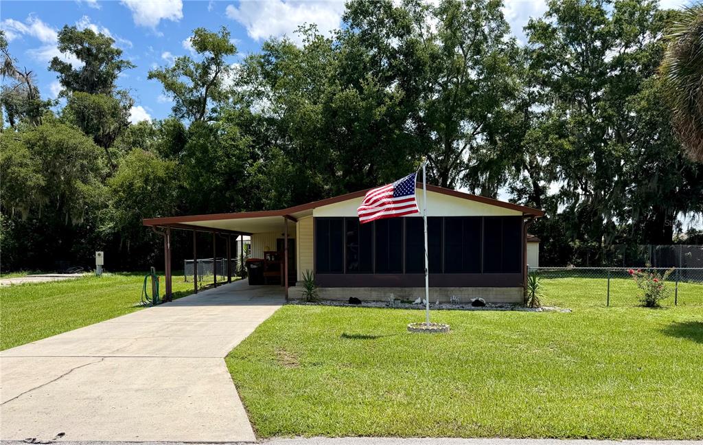 A single-story house with a screened-in porch, a carport, and an American flag in front — 11107 SE 66TH TERRACE, BELLEVIEW, FL
