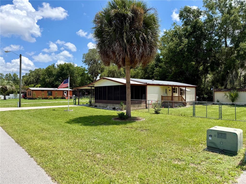 A single-story mobile home with a screened porch and an American flag in the yard — 11107 SE 66TH TERRACE, BELLEVIEW, FL