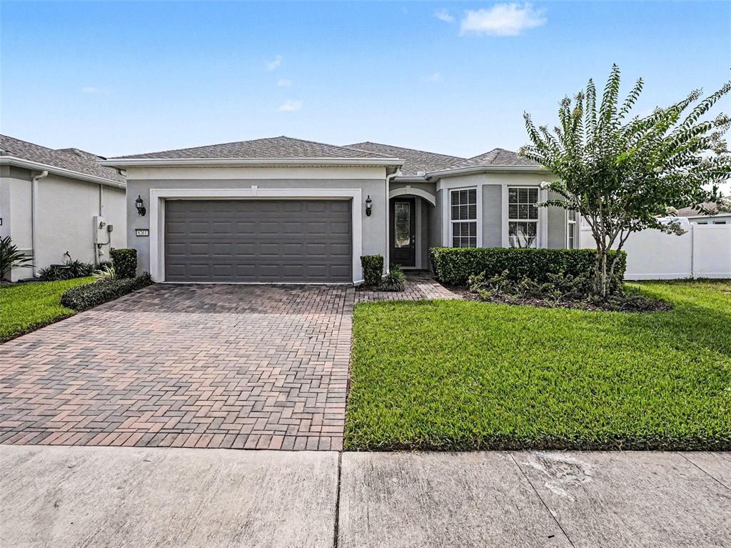 A single-story house features a gray exterior, a brick paver driveway, and a manicured lawn — 6261 CITRUS GROVE COURT, ST CLOUD, FL
