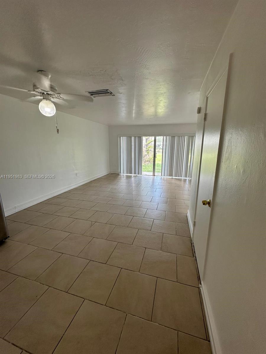 A room with beige tile flooring, a ceiling fan, and sliding glass doors — 7344 SW 82nd St # C115, Miami FL 33143, MIAMI, FL