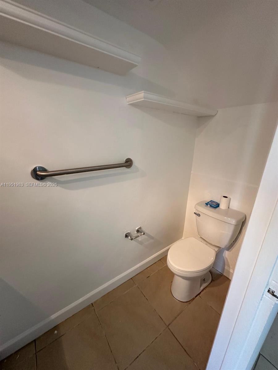 A small bathroom features a white toilet, a grab bar, and a wall-mounted shelf — 7344 SW 82nd St # C115, Miami FL 33143, MIAMI, FL