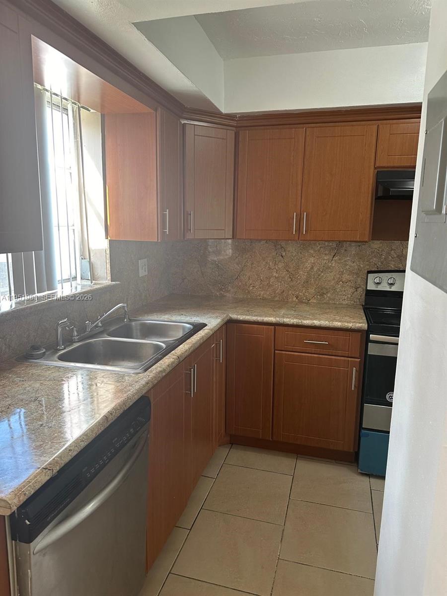 A kitchen features wood cabinets, granite countertops, a stainless steel sink, and tile flooring — 7344 SW 82nd St # C115, Miami FL 33143, MIAMI, FL