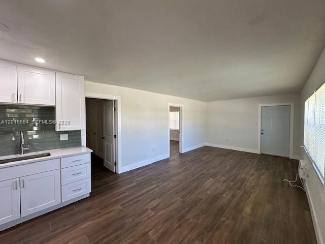 A kitchen with white cabinets and a green backsplash opens into a spacious living area — 101 W 11th St # 2, Riviera Beach FL 33404, RIVIERA BEACH, FL