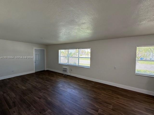 An empty room features wood-look tile flooring, white walls, and two windows — 101 W 11th St # 2, Riviera Beach FL 33404, RIVIERA BEACH, FL