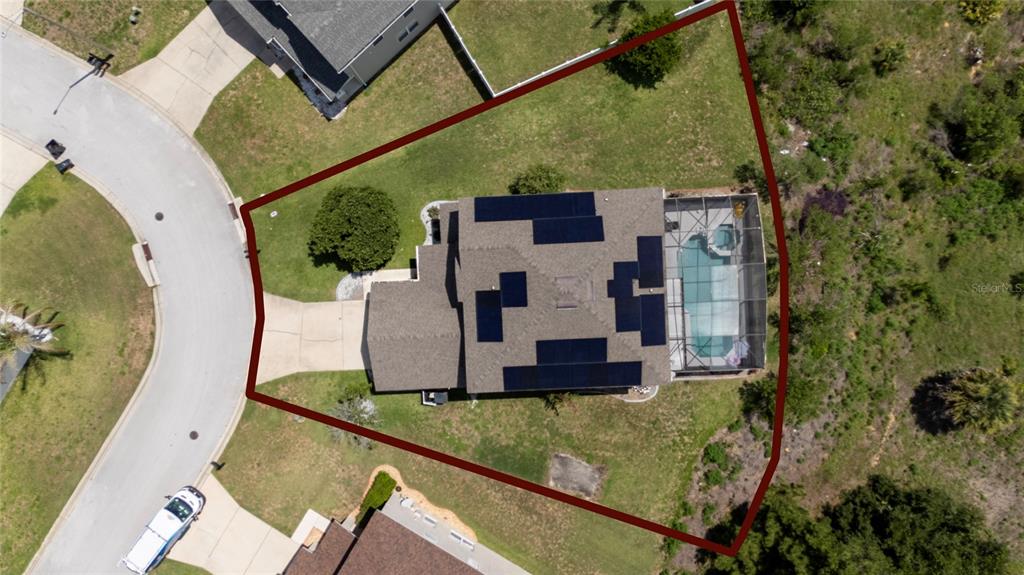 An aerial view shows a house with solar panels and a screened-in pool — 130 BACOPA PASS, DAVENPORT, FL