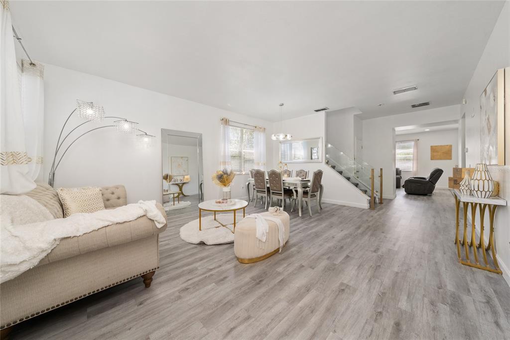 A bright living and dining area with light wood flooring, a staircase, and modern furniture — 130 BACOPA PASS, DAVENPORT, FL
