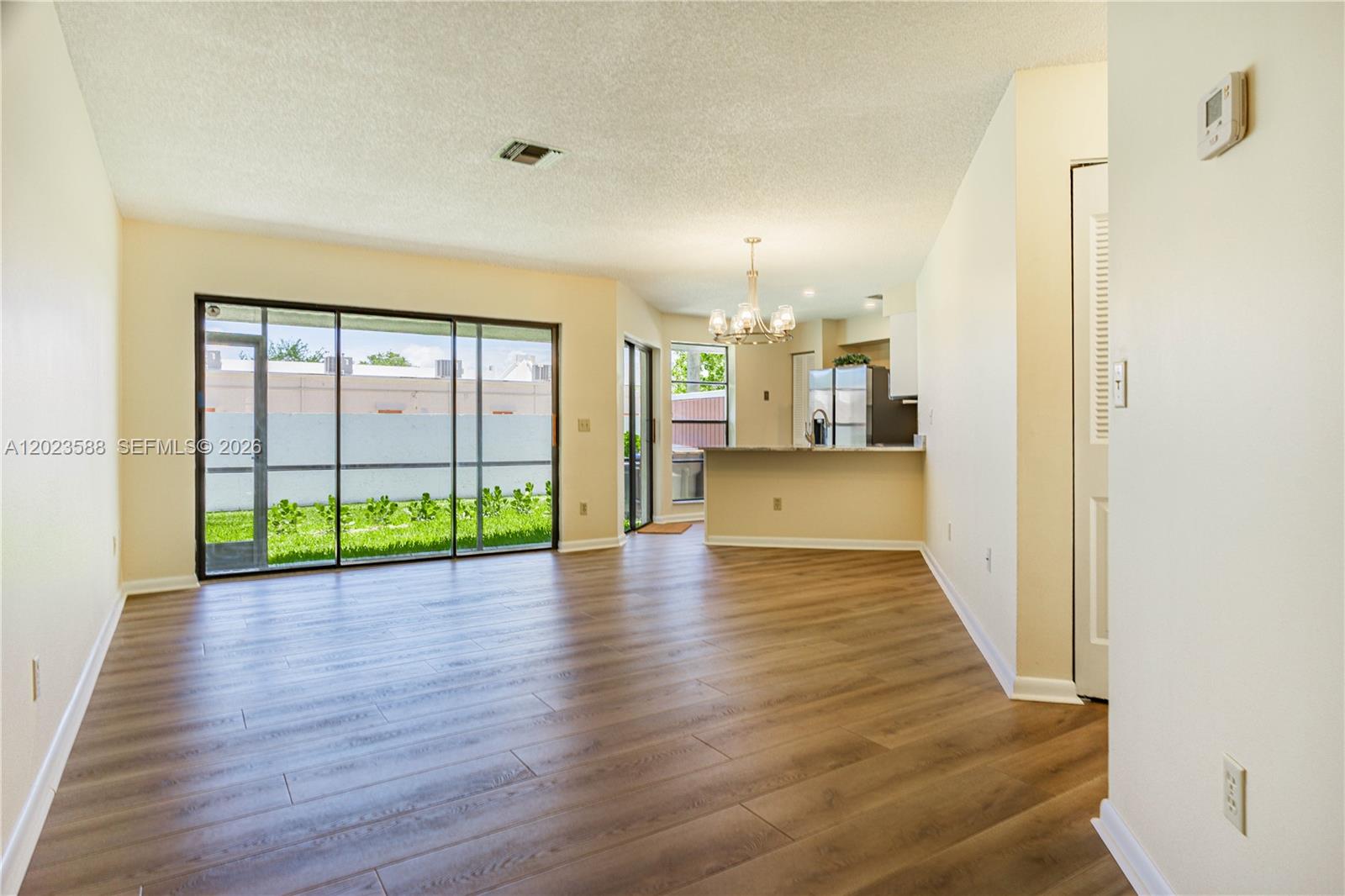 An open-plan living area features wood-look flooring, a kitchen with a breakfast bar, and sliding doors — 275 NW 36th Ave # 275, Deerfield Beach FL 33442, DEERFIELD BEACH, FL