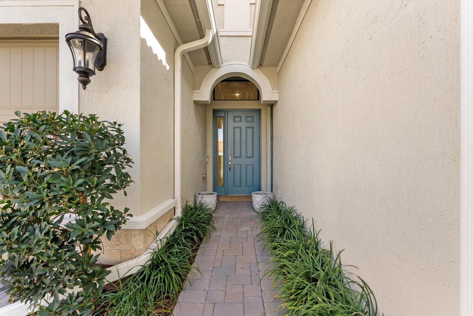 A stone walkway leads to a blue front door framed by an arched entryway — 11770 Leon Circle S, Parkland FL 33076, PARKLAND, FL