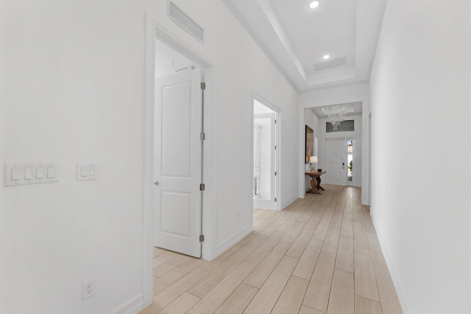 A bright hallway features white walls, light wood-look tile flooring, and recessed tray ceilings — 11770 Leon Circle S, Parkland FL 33076, PARKLAND, FL