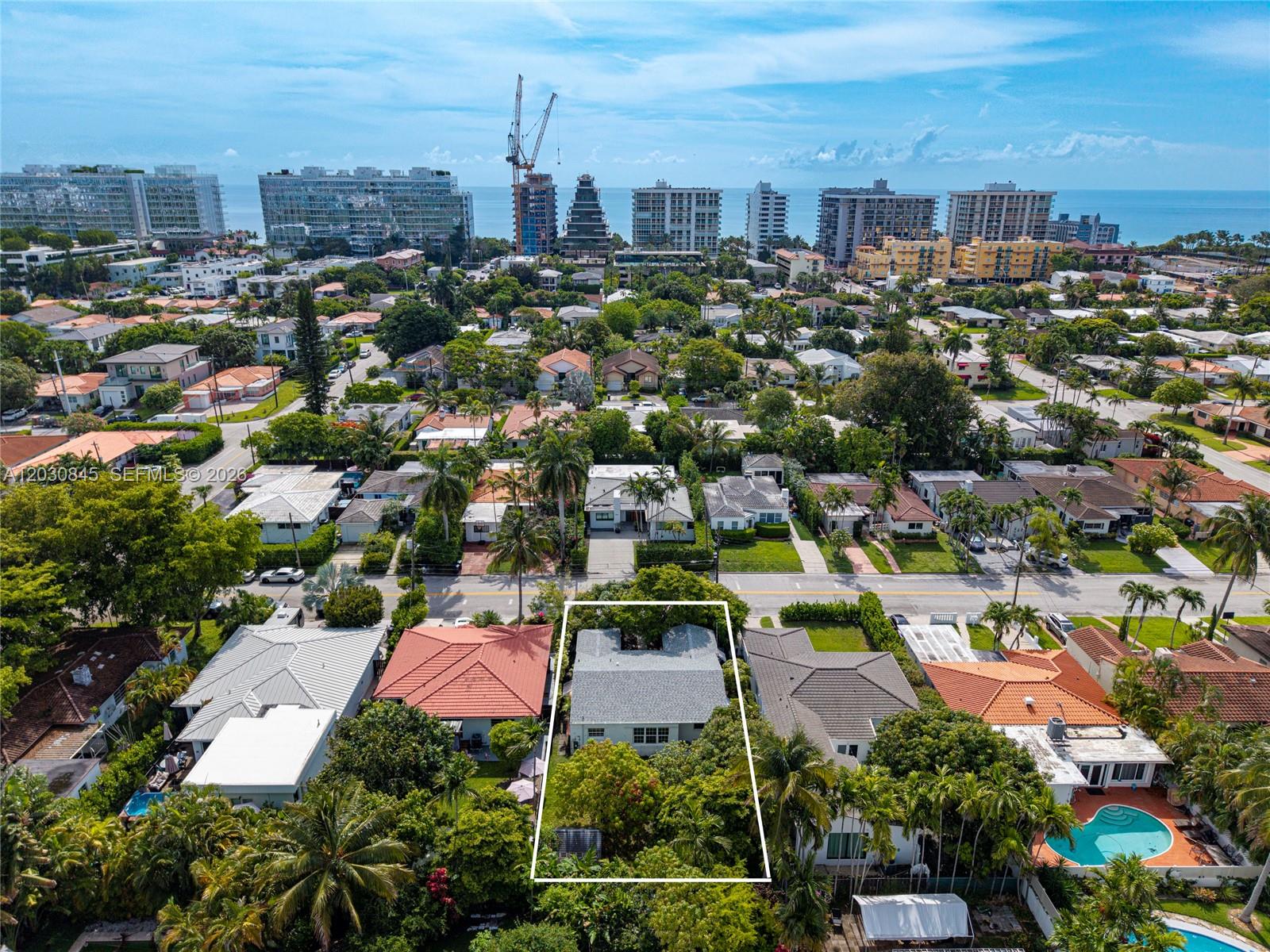 An aerial view shows a single-story house with a grey roof surrounded by lush trees — 8942 Carlyle Ave, Surfside FL 33154, SURFSIDE, FL