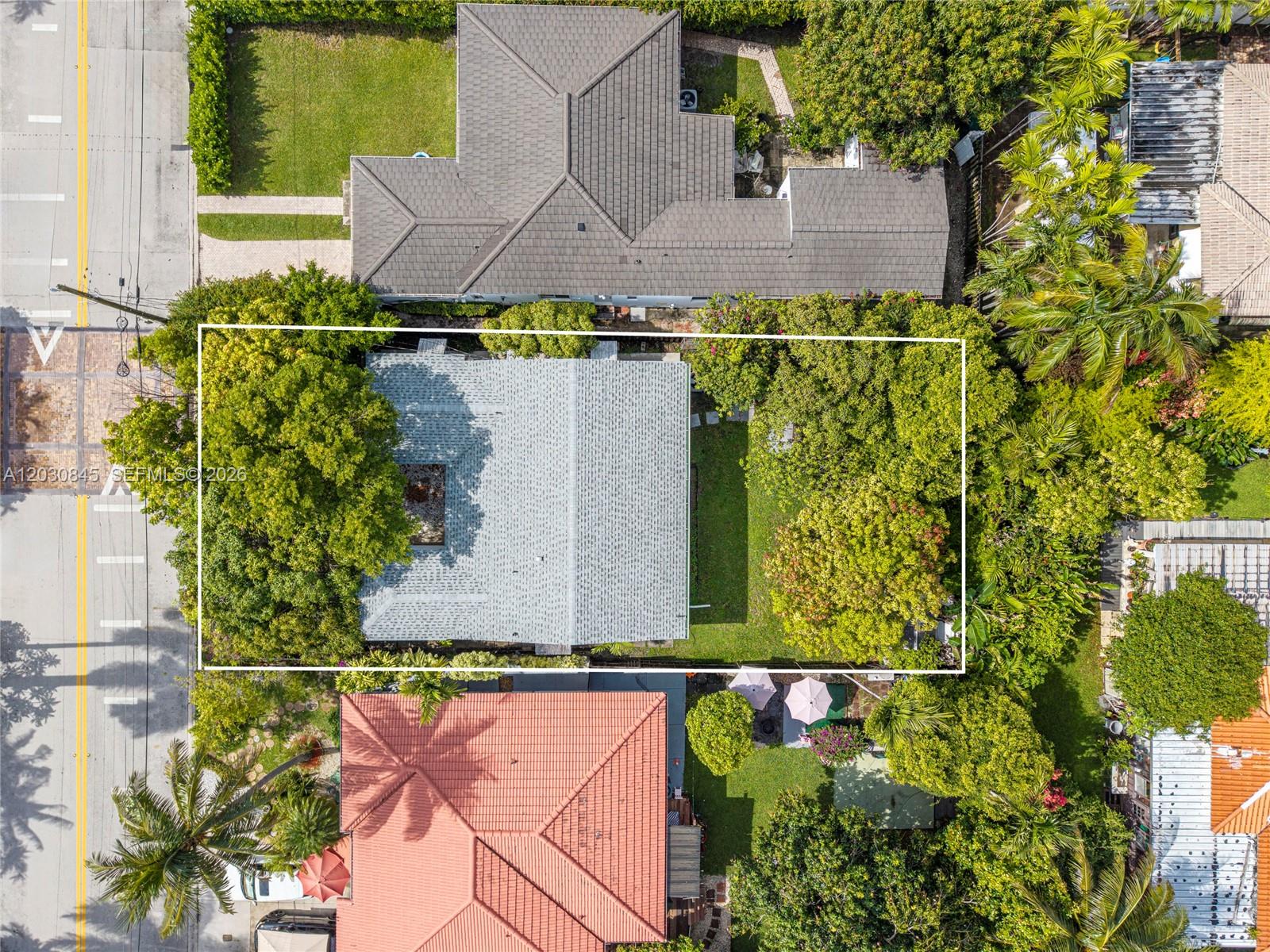 An aerial view shows a house with a gray roof surrounded by trees and lawns — 8942 Carlyle Ave, Surfside FL 33154, SURFSIDE, FL