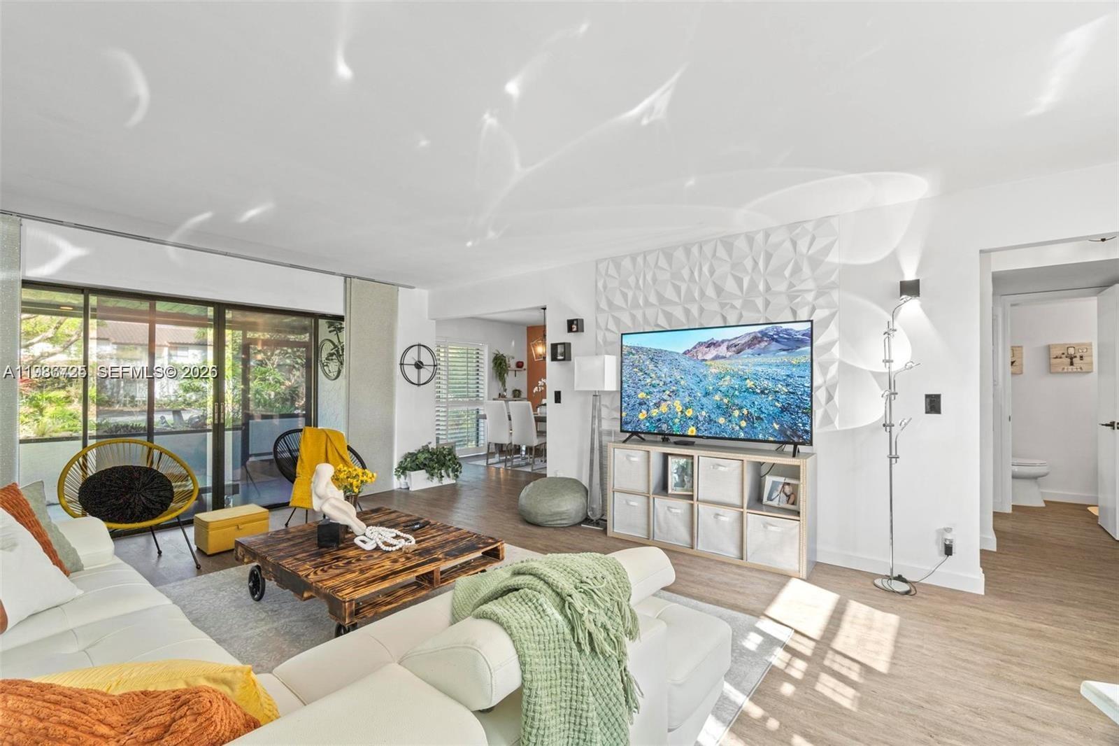 A living room features a white sectional sofa, a pallet coffee table, and a television — 149 NW 70th St # 101C, Boca Raton FL 33487, BOCA RATON, FL