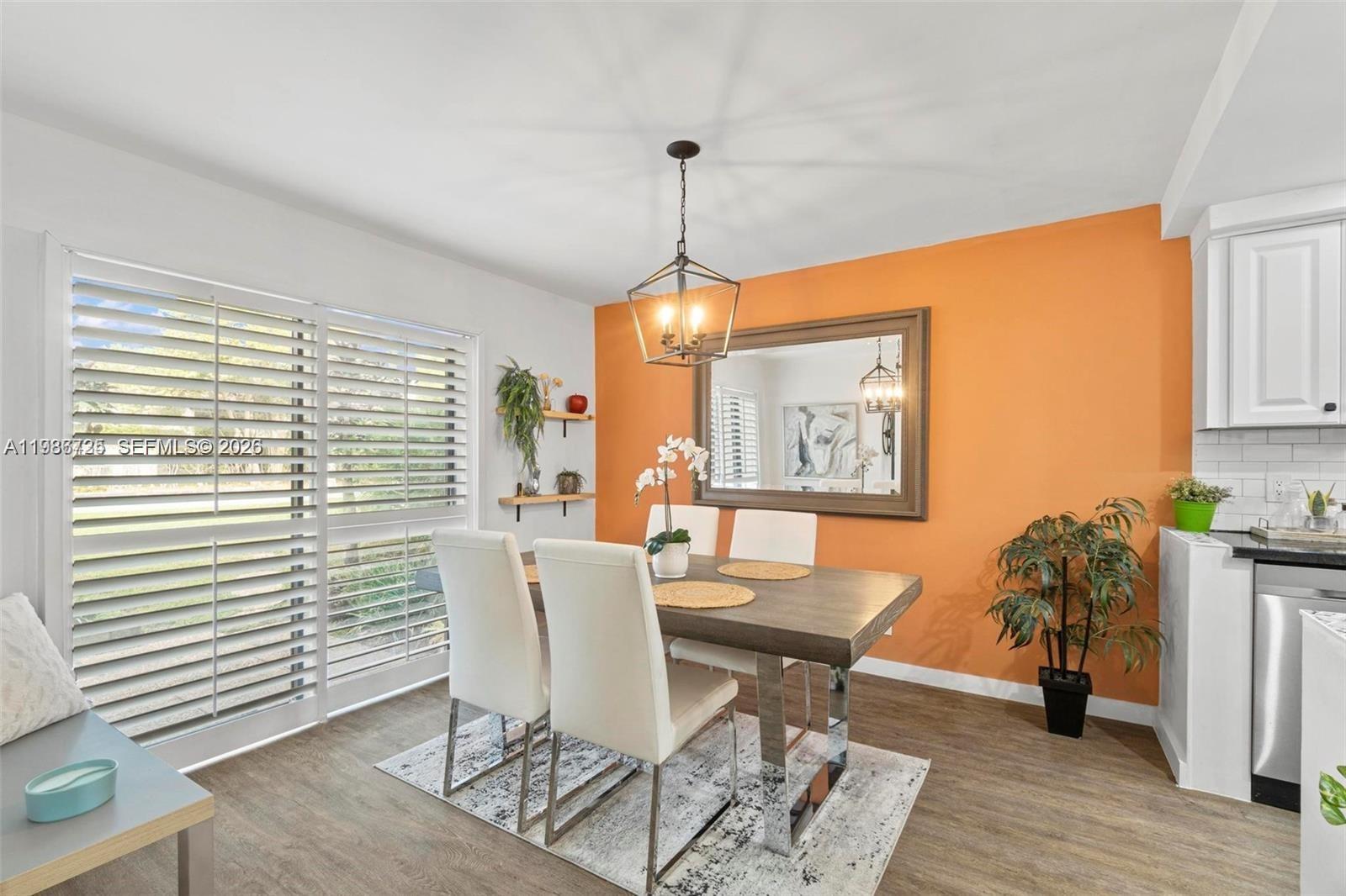 A dining area features a wooden table, white chairs, an orange accent wall, and shutters — 149 NW 70th St # 101C, Boca Raton FL 33487, BOCA RATON, FL