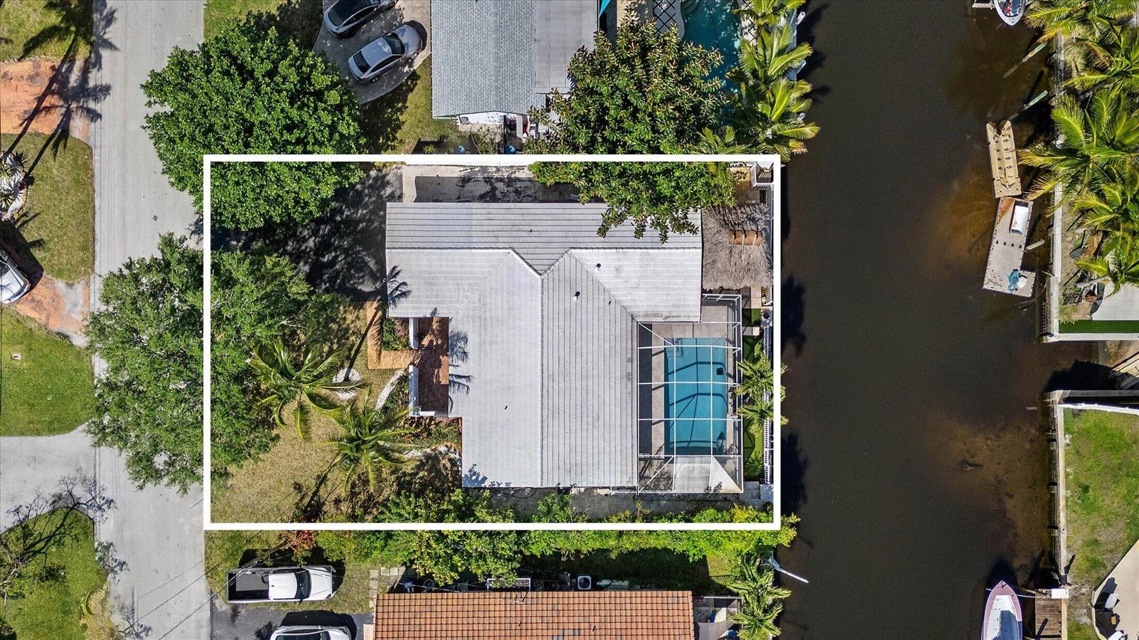 An aerial view of a house with a metal roof, screened pool, and canal access — 421 SW 18th Street, Pompano Beach FL 33060, POMPANO BEACH, FL