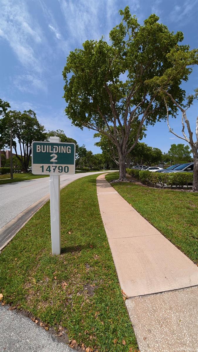 A sign labeled Building 2 stands beside a sidewalk next to a road and trees — 14790 Bonaire Boulevard # 210, Delray Beach FL 33446, DELRAY BEACH, FL