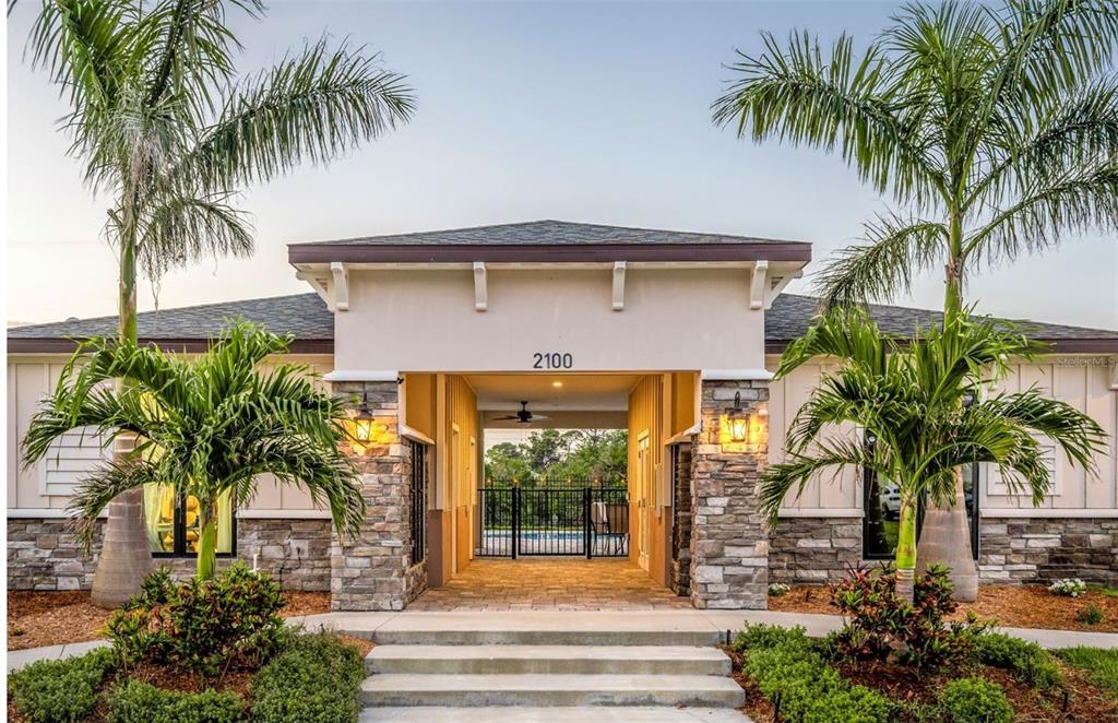 A building entrance with stone pillars, a covered walkway, and palm trees in the foreground — 3301 WHITNEY ROAD UNIT 2102, 2104, 2106, Et al., CLEARWATER, FL