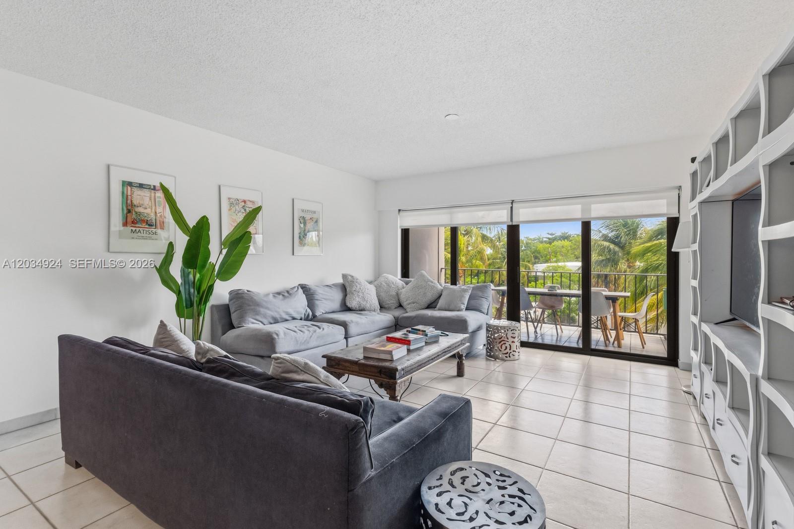 A living room features a sectional sofa, a coffee table, and a balcony with greenery — 575 Crandon Blvd # 413, Key Biscayne FL 33149, KEY BISCAYNE, FL