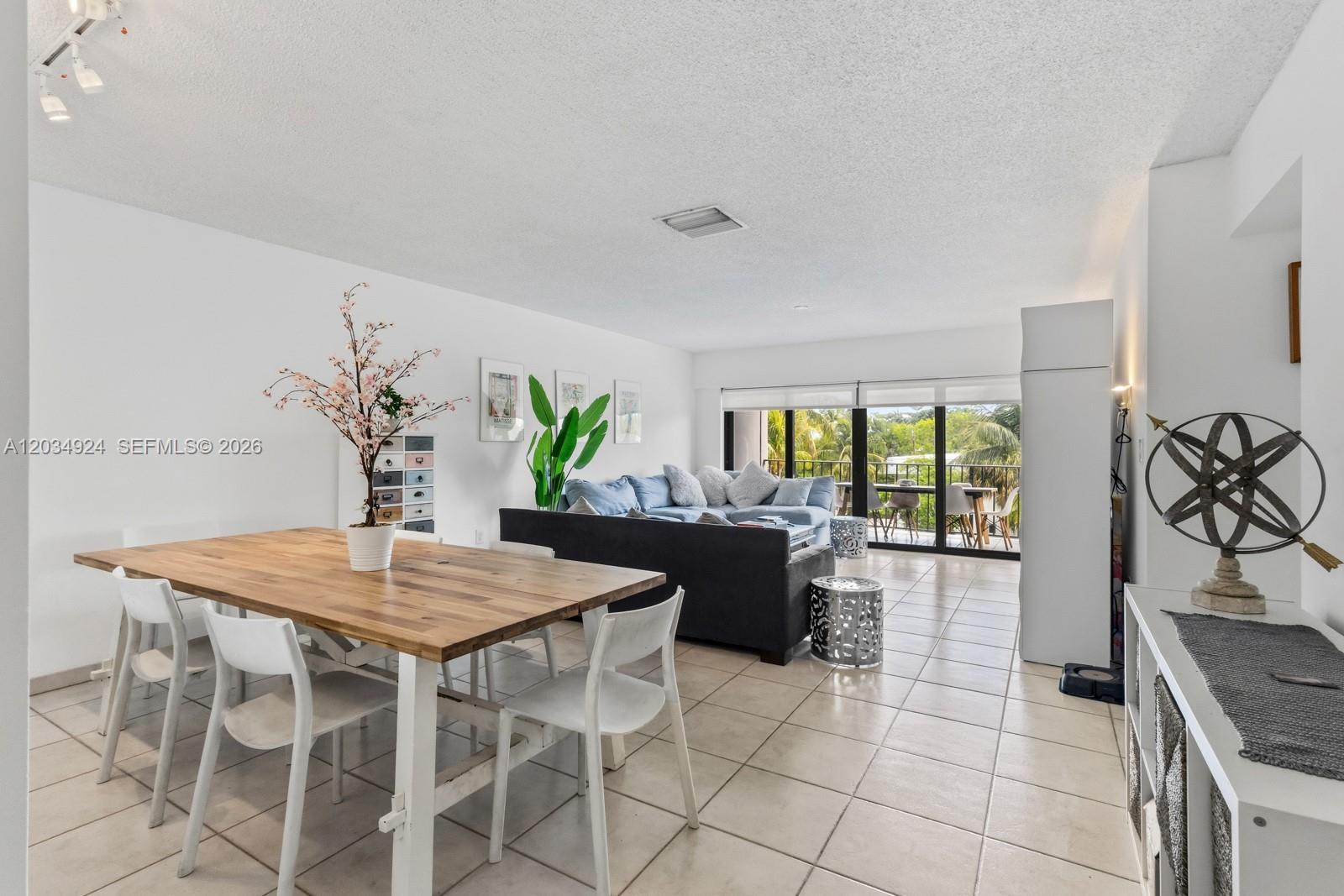 A dining area and living room with tile floors, a wooden table, and a balcony — 575 Crandon Blvd # 413, Key Biscayne FL 33149, KEY BISCAYNE, FL