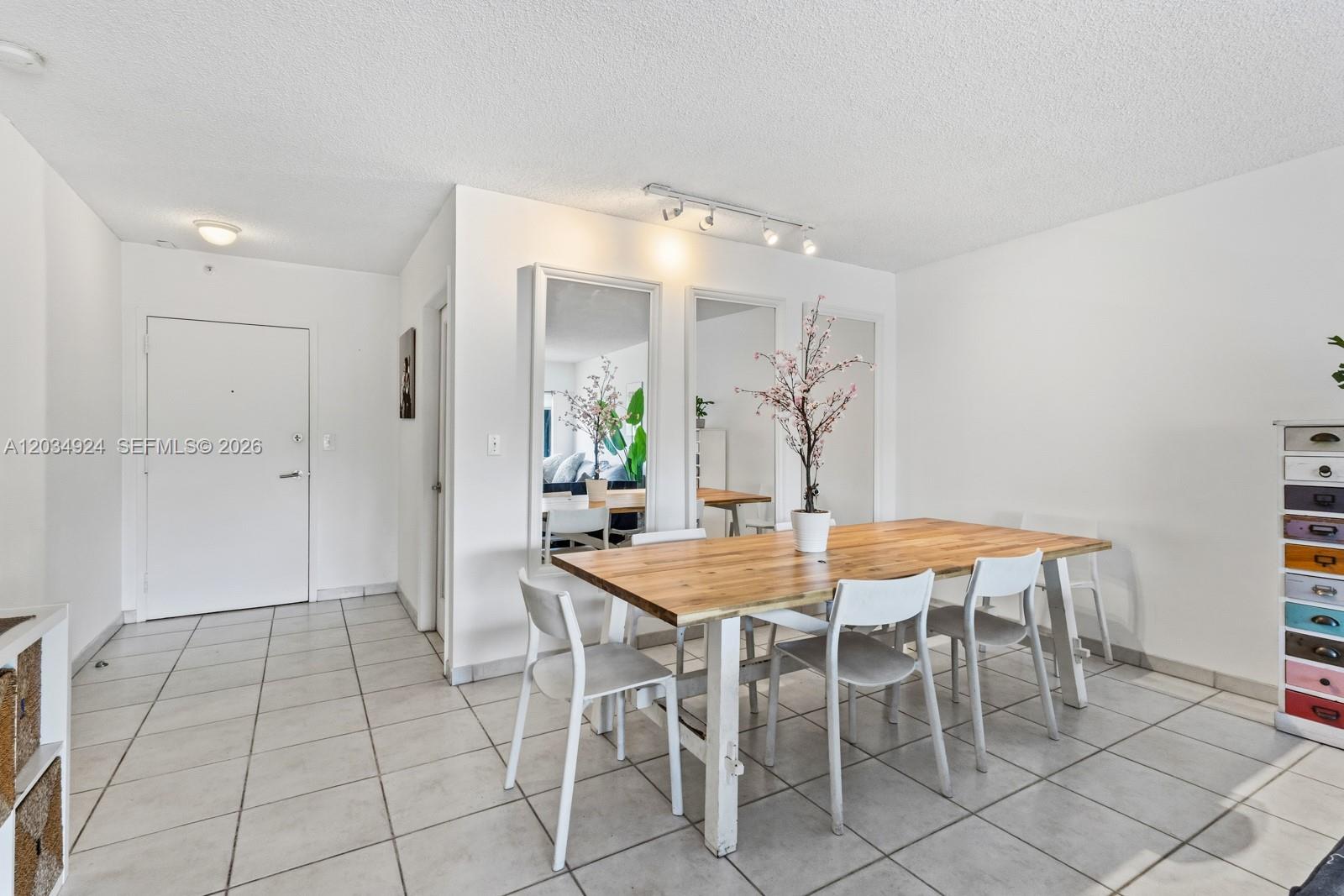 A dining area features a wooden table, white chairs, wall mirrors, and tiled flooring — 575 Crandon Blvd # 413, Key Biscayne FL 33149, KEY BISCAYNE, FL