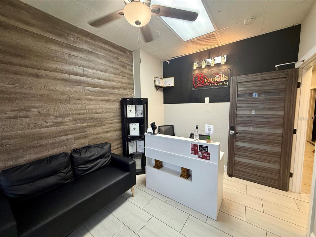 A reception area features a white desk, a black sofa, and wood-look wall paneling — 5404 HOOVER BOULEVARD UNIT 24, TAMPA, FL