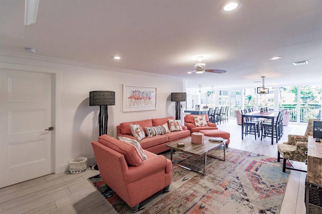 A living room features a coral sofa, patterned rug, and an open-concept dining area beyond — 1125 W PEPPERTREE DRIVE UNIT 102, SARASOTA, FL