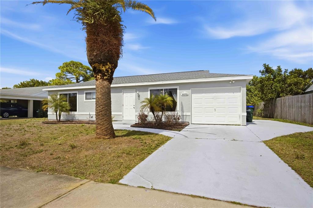 A single-story house with a gray exterior, a white garage door, and a palm tree — 8170 LOMBRA AVENUE, NORTH PORT, FL
