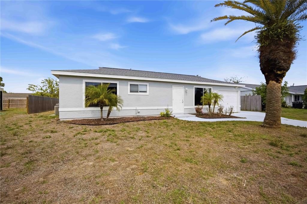A single-story house with light gray siding, a white front door, and a palm tree — 8170 LOMBRA AVENUE, NORTH PORT, FL