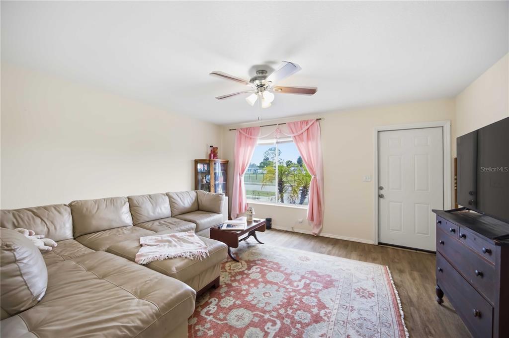 A living room features a beige sectional sofa, a patterned rug, and a ceiling fan — 8170 LOMBRA AVENUE, NORTH PORT, FL