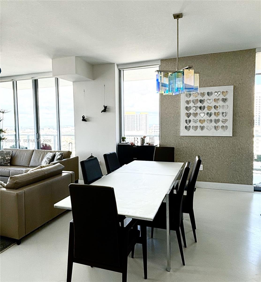 A dining area features a white table, black chairs, a glass chandelier, and floor-to-ceiling windows — 79 SW 12th St, Miami FL 33130, MIAMI, FL
