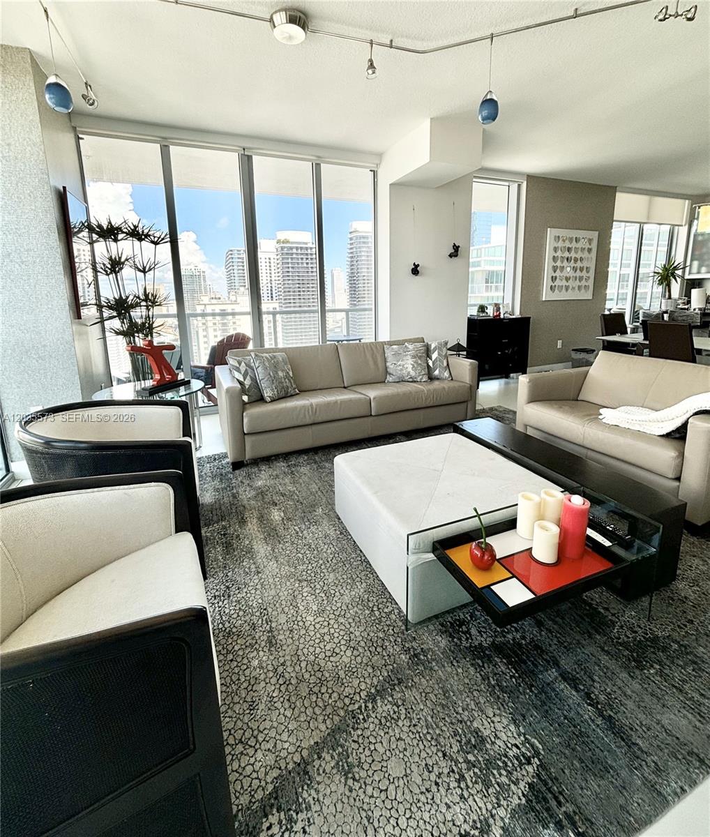 A modern living room features two beige sofas, armchairs, and a large patterned area rug — 79 SW 12th St, Miami FL 33130, MIAMI, FL