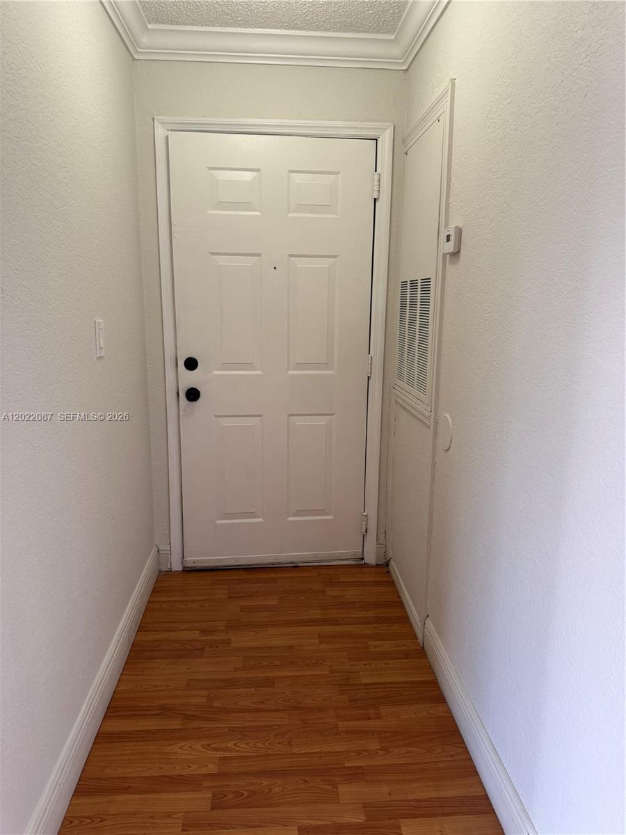 A narrow entryway features a white door, wood-look flooring, and a wall-mounted ventilation grate — 15689 SW 106th Ln # 718, Miami FL 33196, MIAMI, FL
